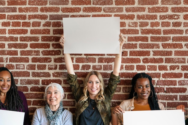 Mujeres diversas que muestran la plantilla de carteles en blanco