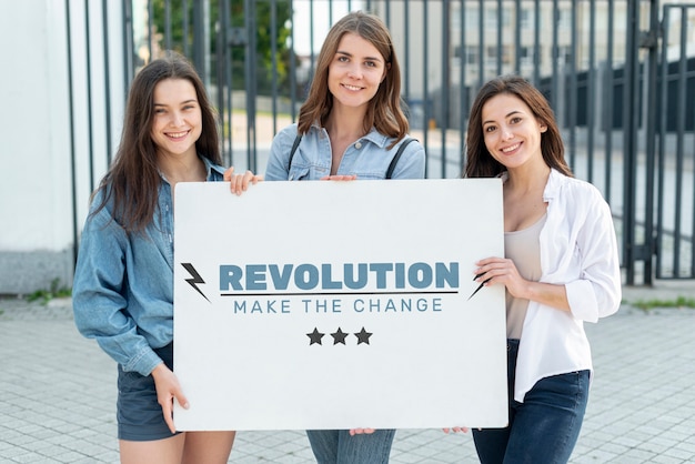 Mujeres felices que sostienen el tablero con la maqueta