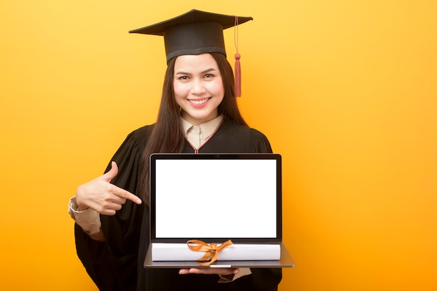 Mulher bonita em vestido de formatura está segurando maquete de laptop