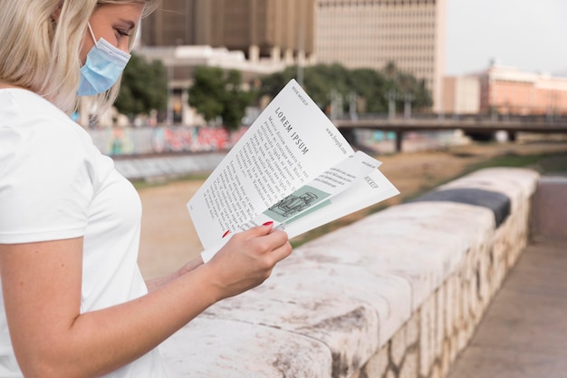 Mulher com máscara lendo livro na rua