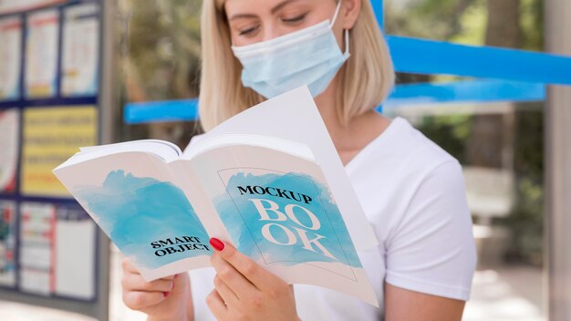 Mulher com máscara na rua lendo livro