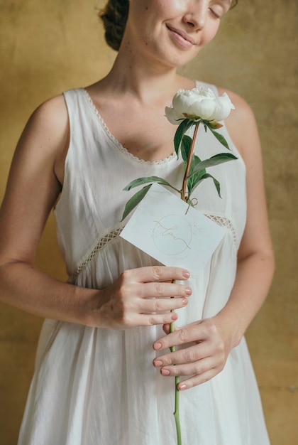 Mulher com uma flor de snowboard de paeonia branca e uma maquete de cartão