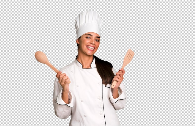 Mulher de chef muito jovem e expressiva hispânica com ferramentas de cozinheiro