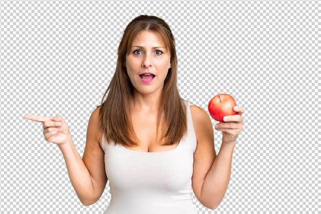 PSD mulher de meia-idade com uma maçã sobre fundo isolado surpresa e apontando o dedo para o lado