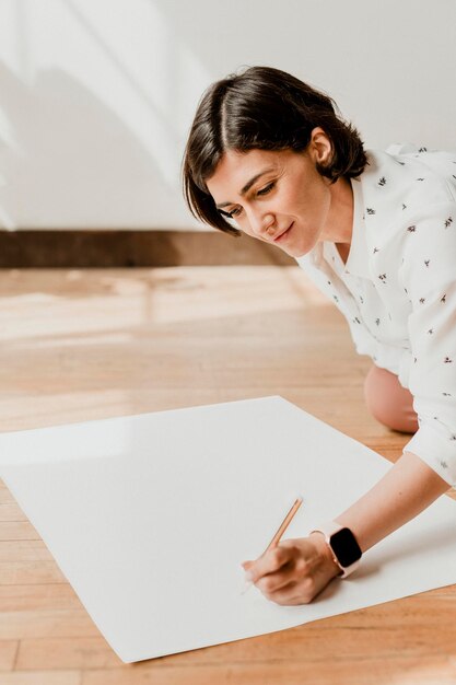 Mulher feliz escrevendo em uma maquete de papel gráfico branco