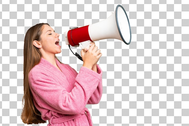 Mulher jovem em roupão de banho sobre fundo de chave de croma isolado gritando através de um megafone