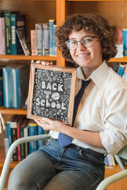 Mulher jovem, segurando, slate, mockup, em, biblioteca