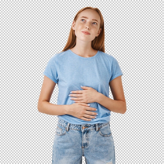 Mulher lembrando-se da comida saborosa que comeu em um novo restaurante esfregando a barriga ou a barriga olhando para o canto superior esquerdo nostálgico e feliz gostando de comer refeições deliciosas de pé em camisa azul