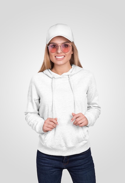 Mulher loira sorridente usando óculos de sol um chapéu branco e um capuz branco