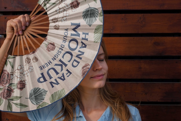 Mulher segurando ventilador de mão com design de maquete