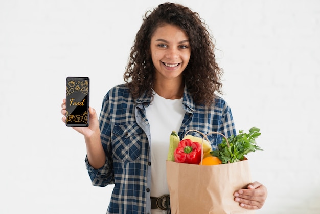 PSD mulher sorridente com telefone e legumes