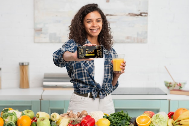 PSD mulher sorridente segurando móvel e bebendo suco