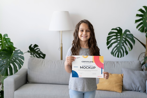 Niña en casa con una maqueta de certificado