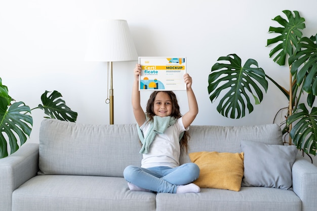 PSD niña en casa con una maqueta de certificado