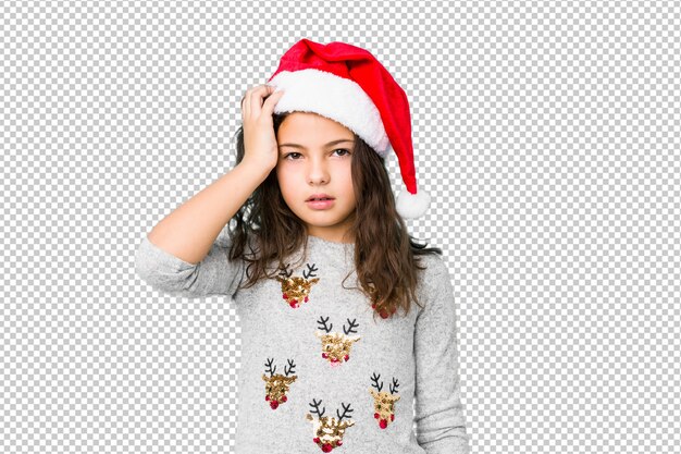 Niña celebrando el día de Navidad cansado y con mucho sueño manteniendo la mano en la cabeza.