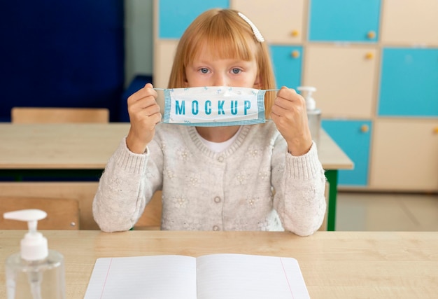 Niña con una maqueta de máscara médica