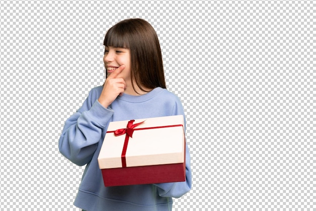 Niña sosteniendo un regalo sobre un fondo clave de croma aislado pensando en una idea y mirando de lado
