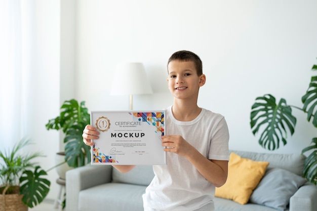 Niño pequeño en casa con una maqueta de certificado