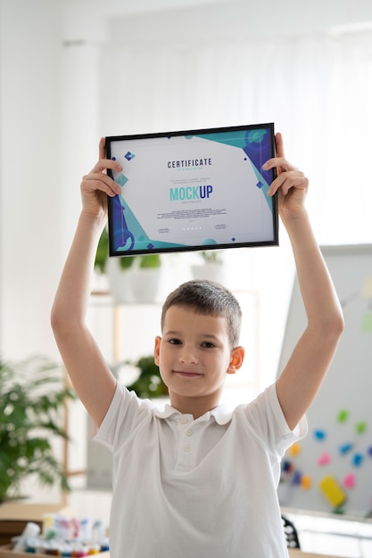 Niño pequeño en casa con una maqueta de certificado