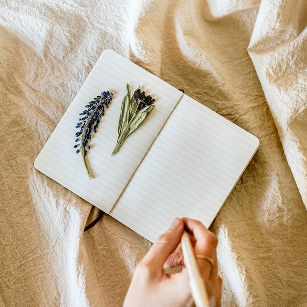 Öffnetes Notebook-PSD-Mockup mit Blumen auf einer Leinendecke