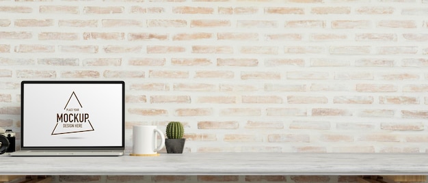 PSD ordinateur portable avec écran de maquette sur un bureau en marbre avec appareil photo et décorations avec mur de briques