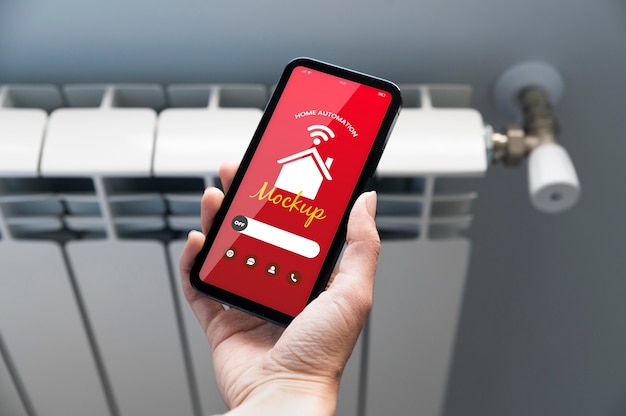 Osoba drží smartphone s aplikací pro automatizaci domácnosti