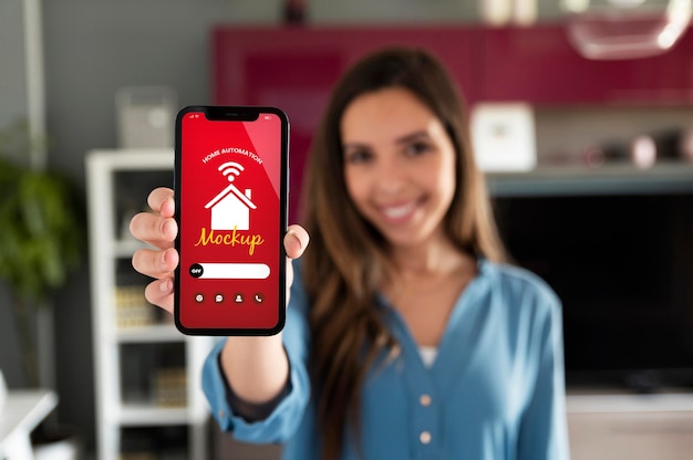 Osoba drží smartphone s aplikací pro automatizaci domácnosti