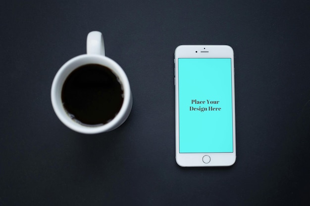 Pantalla azul del teléfono móvil junto a la taza de café negra Mockup PSD