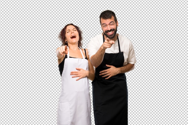 Par de cocineros apuntando con el dedo a alguien y riendo mucho