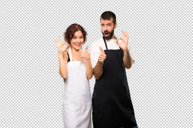 Pareja de cocineros que muestra signo de ok y dando un pulgar arriba gesto con la otra mano