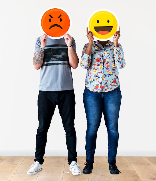 Pareja sosteniendo una cara emoticon expresiva