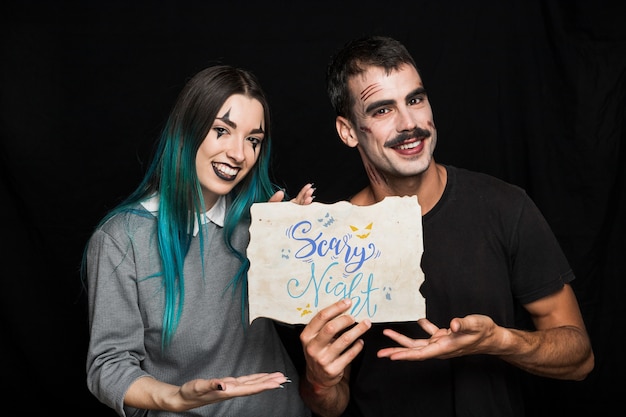 Pareja sujetando papel con lettering de halloween