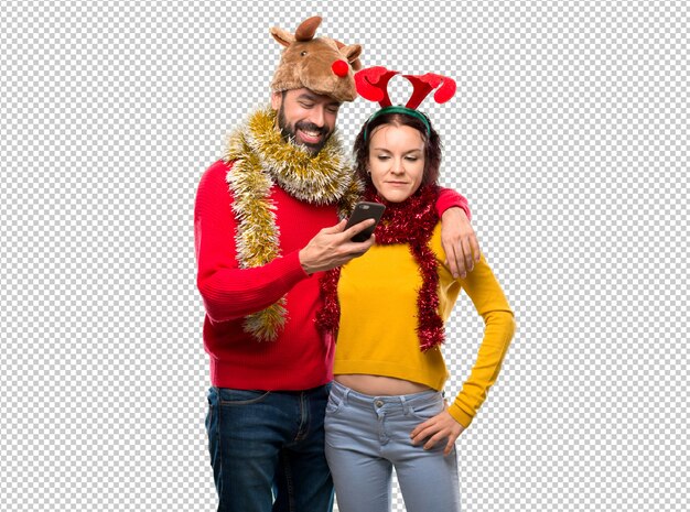 PSD pareja vestida para las vacaciones navideñas sosteniendo un móvil.