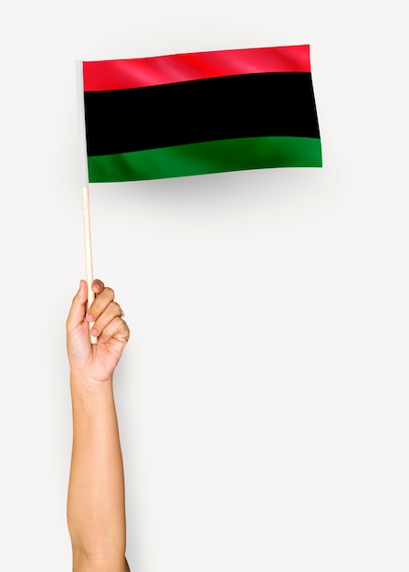 Person, die die Flagge der Panafrikanischen Flagge wellenartig bewegt