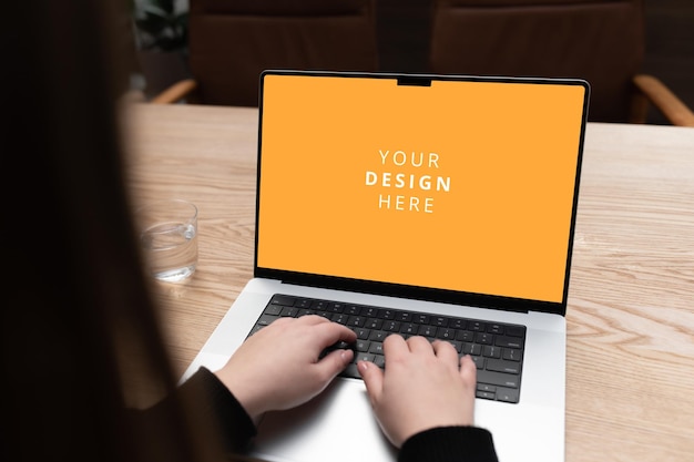Person, die mit den Händen auf der Tastatur mit hölzernem Hintergrund an einem modernen Laptop arbeitet
