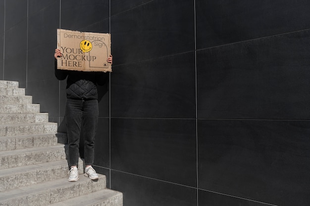 Person hält bei Protest ein Schild mit einer Attrappe