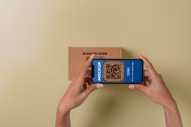 Persona escaneando código qr en caja de cartón con teléfono inteligente