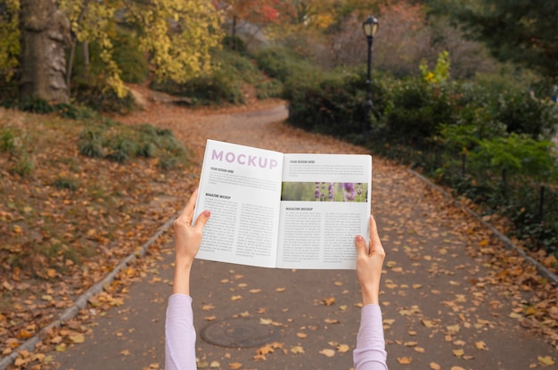 PSD persona con revista de papel al aire libre en la naturaleza