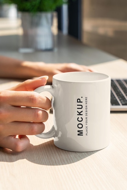 Una persona sosteniendo una maqueta de taza de café.