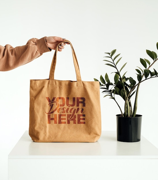 Una persona sostiene una bolsa de mano marrón que dice su diseño aquí.