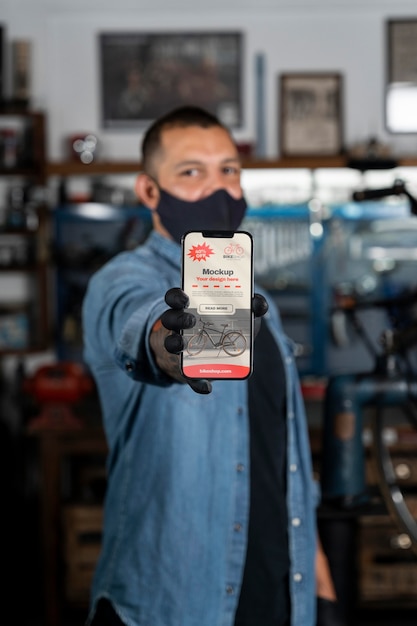 Persona con un teléfono inteligente para diseñar y fabricar bicicletas