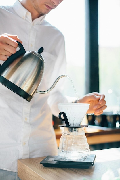 une personne versant une tasse de café d'une cafetière