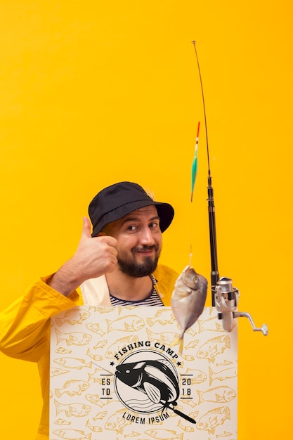 Pescador na capa de chuva, segurando a haste