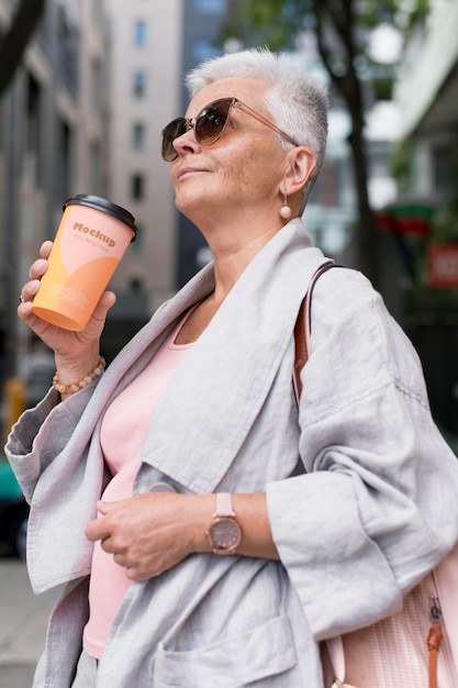 Pessoa idosa segurando uma chávena de café enquanto está na cidade