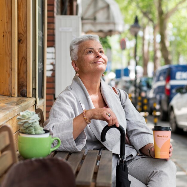 Pessoa idosa segurando uma chávena de café enquanto está na cidade