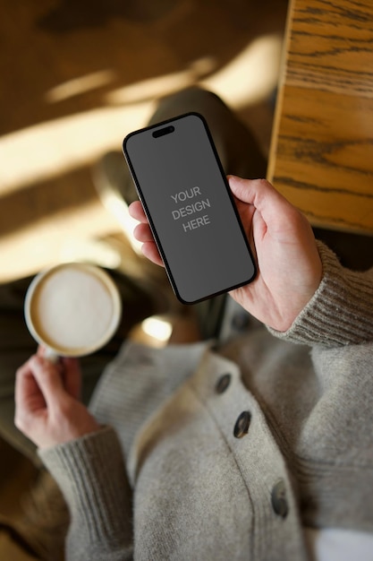 Pessoa segurando um telefone em um café com uma chávena de café