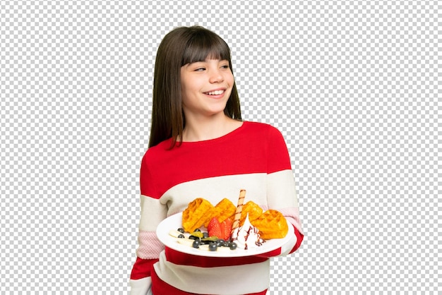 Petite fille tenant des gaufres sur un fond de clé chrome isolé regardant de côté et souriant