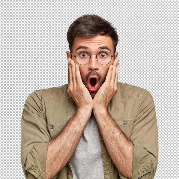 Une photo intérieure d'un homme émotionnellement choqué et non rasé. Un hipster touche les joues avec les deux mains. Une expression effrayée.