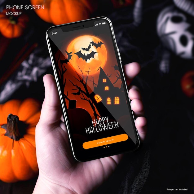 PSD photo d'une main tenant une maquette d'iphone 15 et en arrière-plan se trouvent des décorations d'halloween