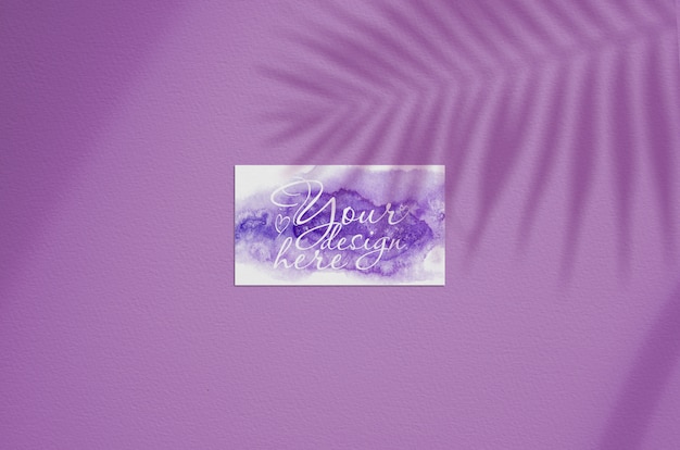 Plantilla de tarjeta de visita sobre un fondo rosa con la sombra de la hoja de palma
